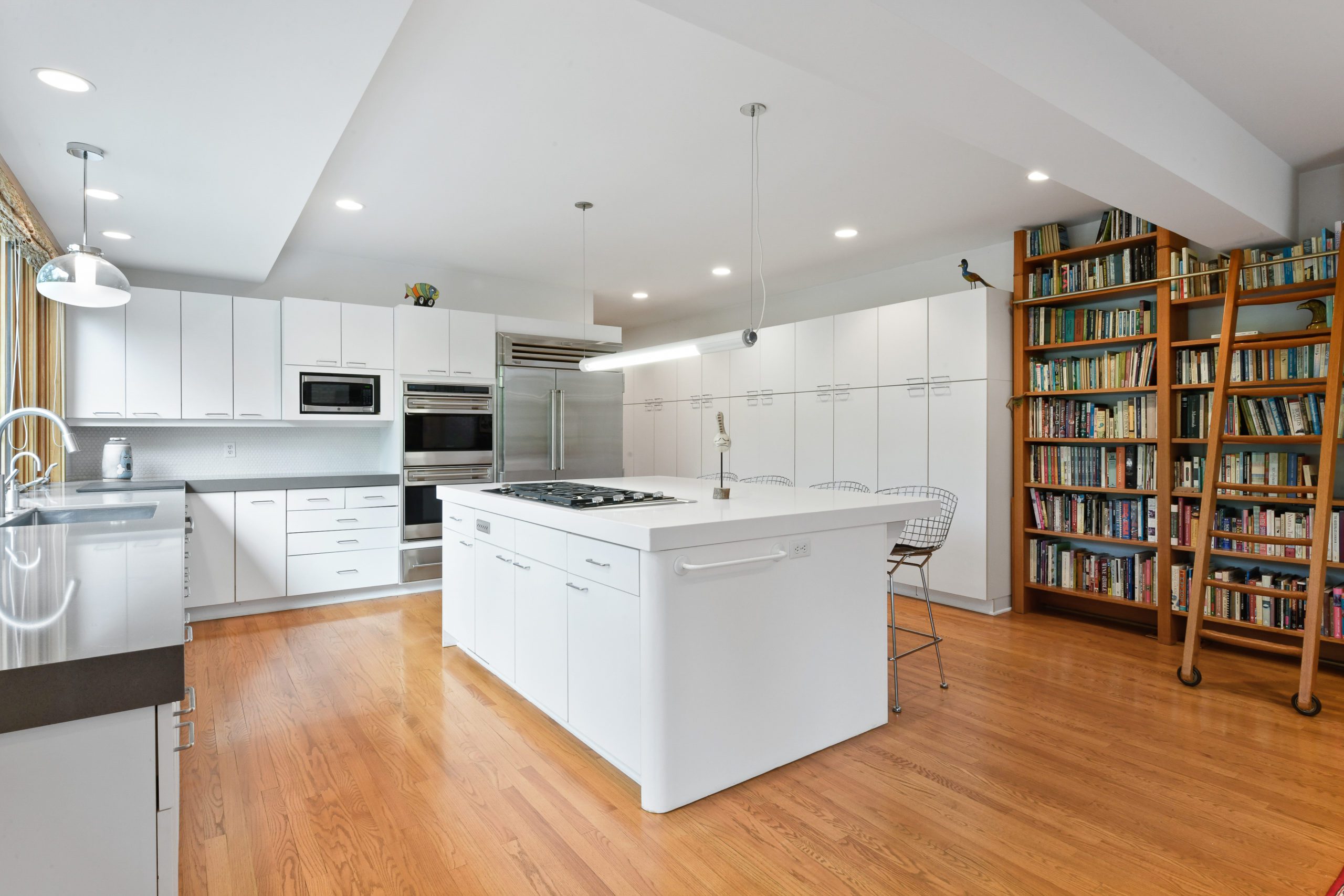 Interior kitchen with white cabinets and appliances and wood flooring